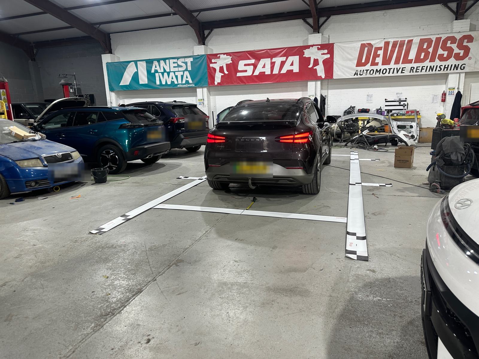 Car positioned on 360° camera calibration lines in a bodyshop in Sheffield